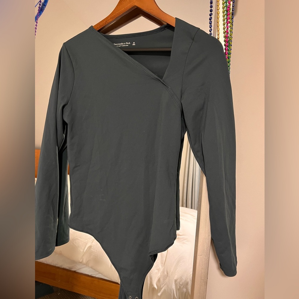 Dark green bodysuit with asymmetrical v cut in neck.